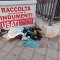 Contenitore indumenti saccheggiato: scarpe ed indumenti a terra in piazza Garibaldi